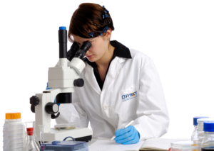 A woman in a lab coat looking through a microscope demonstrating clinical services