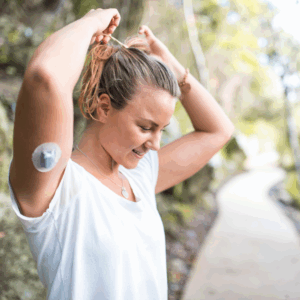 woman in a white shirt exercising while wearing a continuous glucose monitor