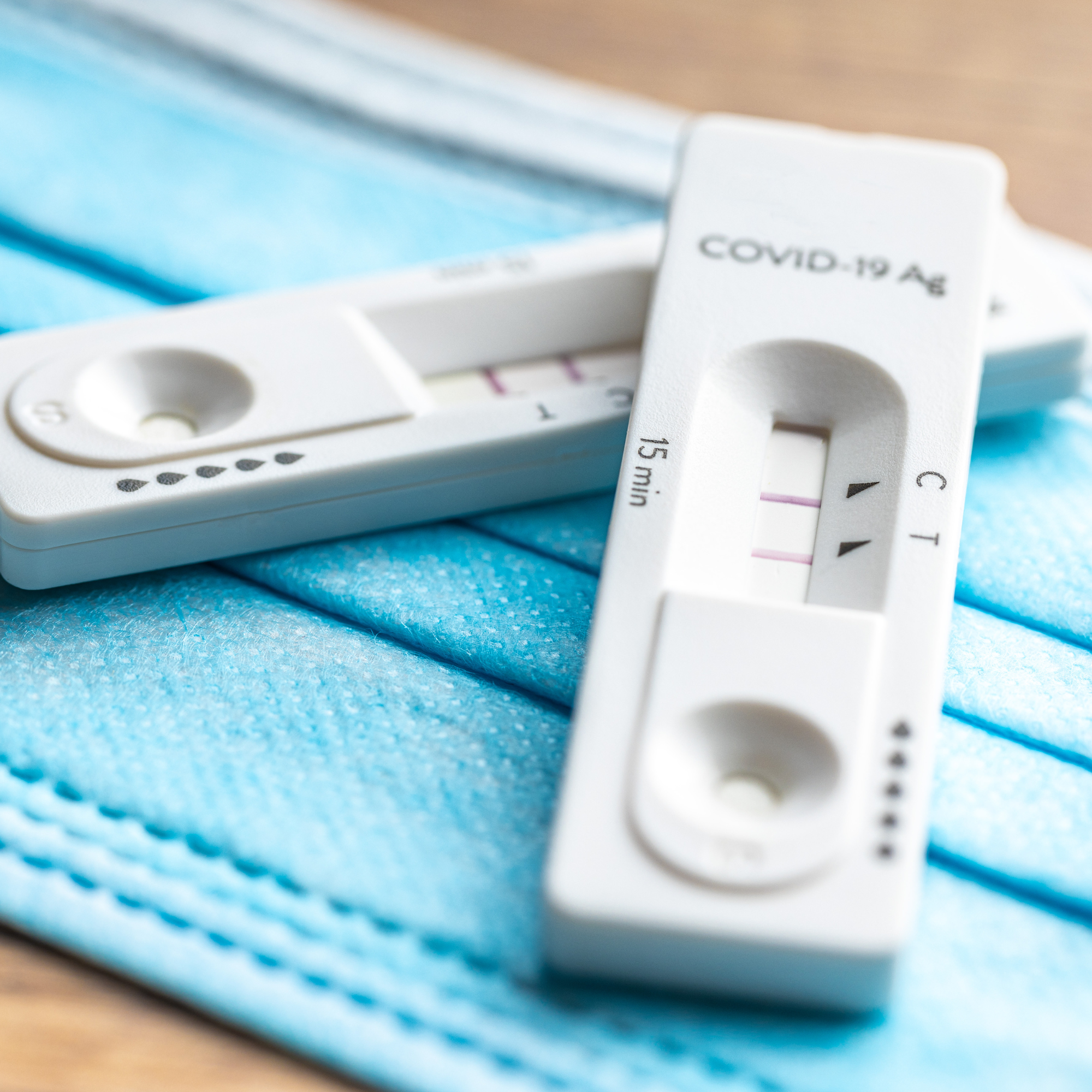 Two COVID rapid tests laying on a surgical mask