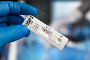 a blue nitrile gloved hand holding a positive strep throat rapid test